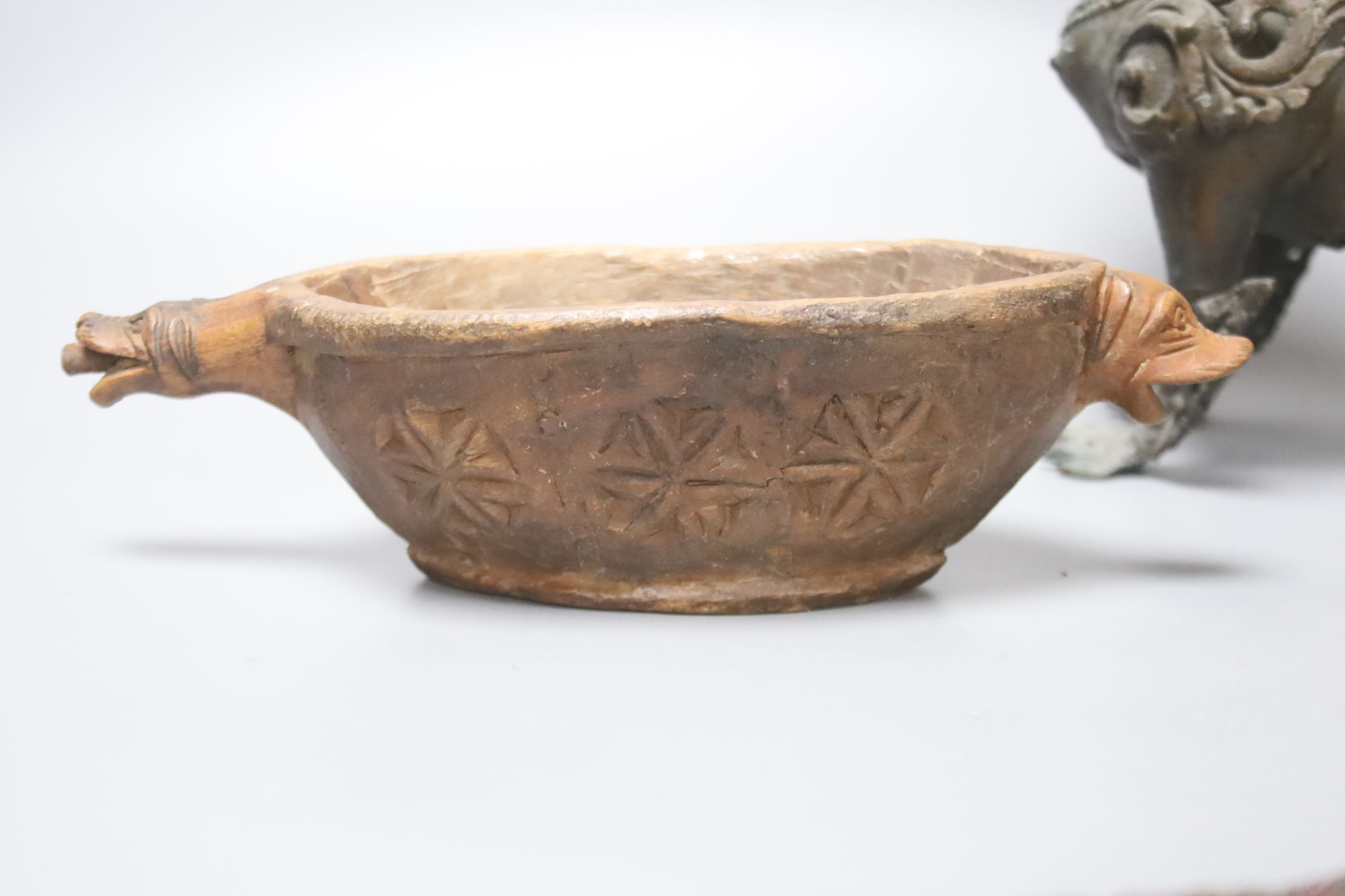 A South East Asian brass Buddhistic lion, carved wood vessel and an African tribal beaded pouch